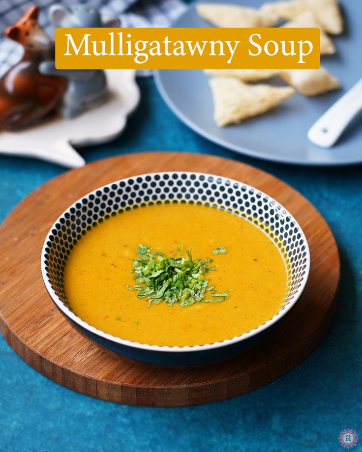 a white bowl filled with soup on top of a blue table next to plates and utensils