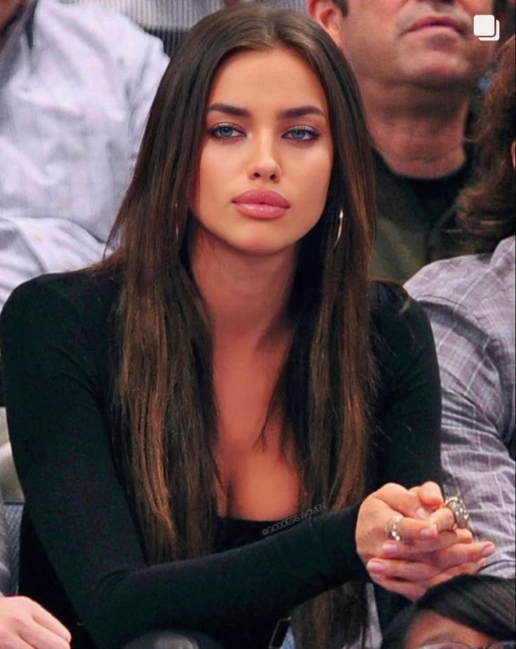 a woman sitting in the stands at a basketball game with her finger on her lips