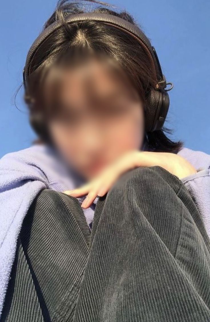 a blurry photo of a woman with headphones on and her hands behind her back