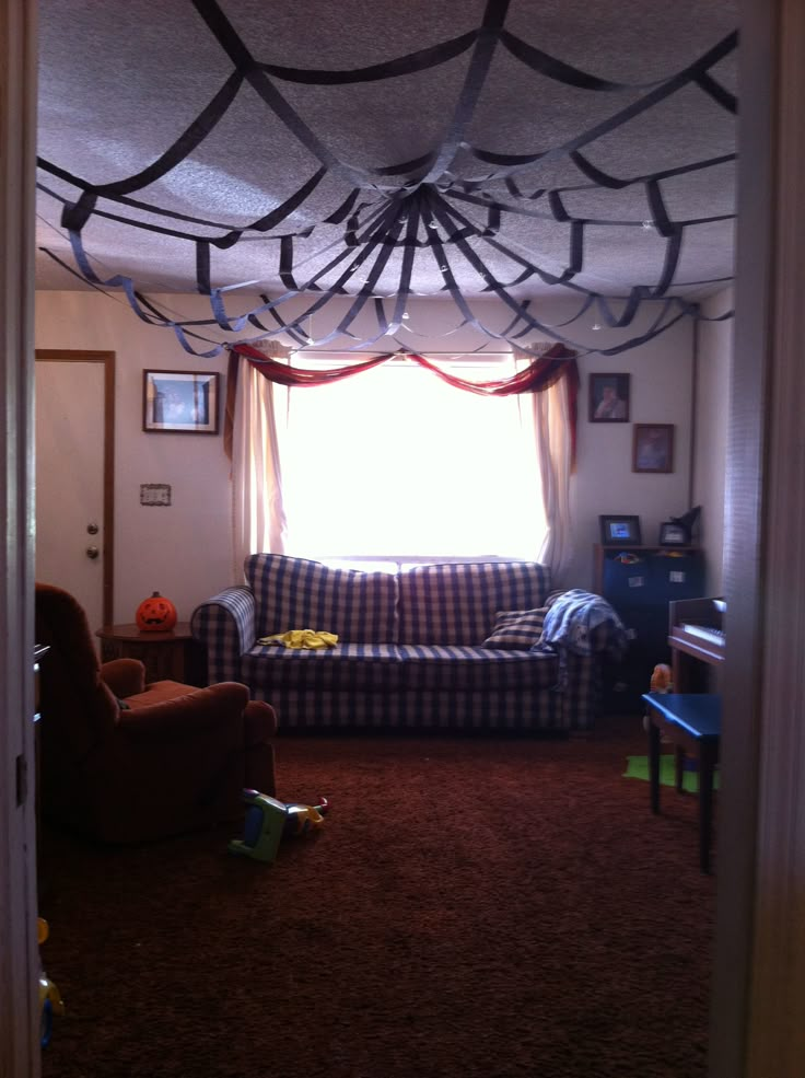 the living room is decorated with spider webs on the ceiling and curtains hanging from the ceiling