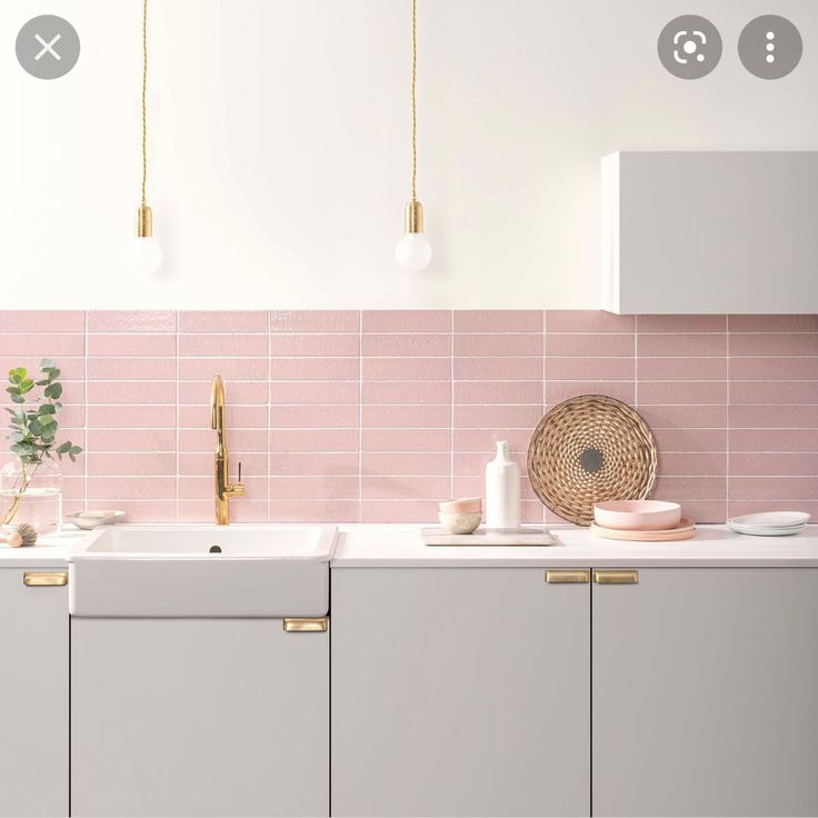 a kitchen with pink tiles and gold handles on the cabinets, counter tops and drawers