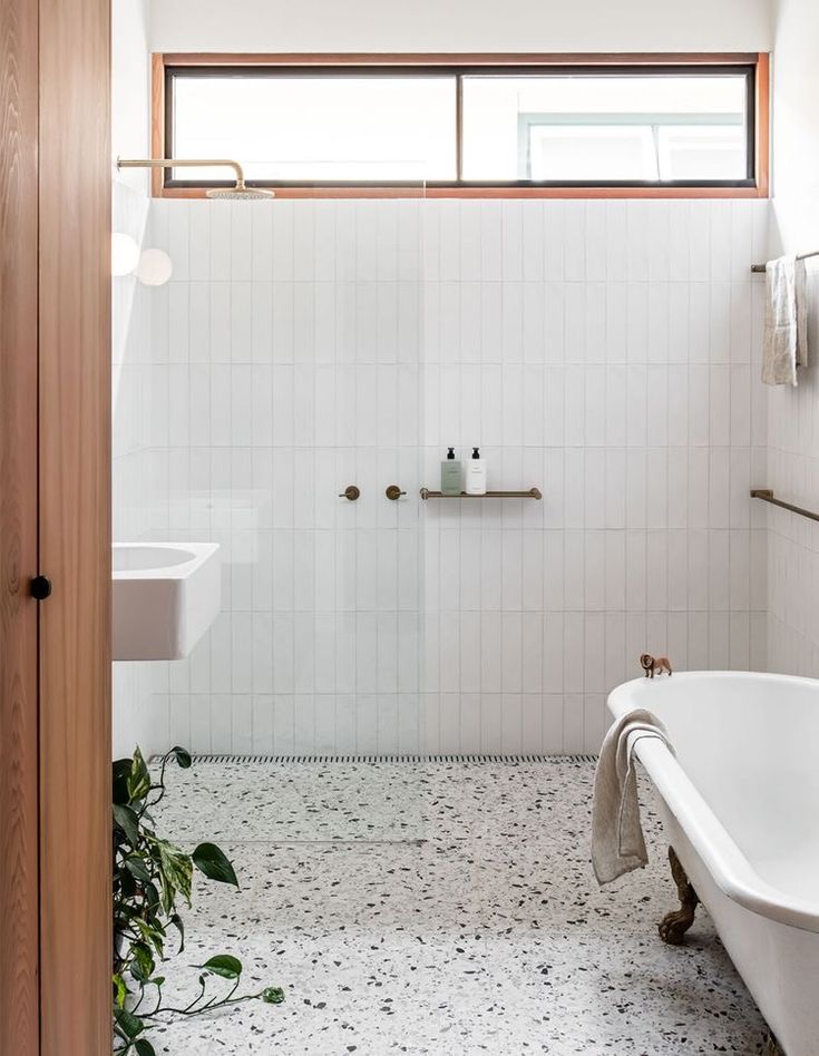 a white bath tub sitting under a window next to a sink