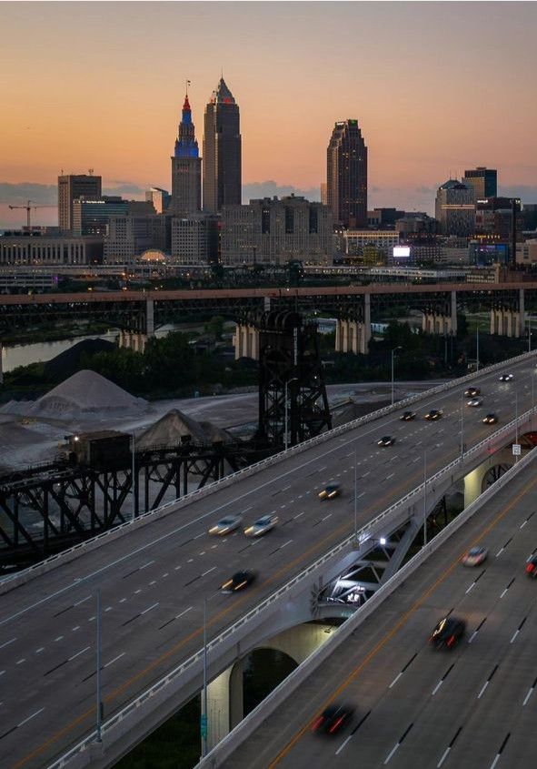 an aerial view of a highway with cars driving on it and the city skyline in the background