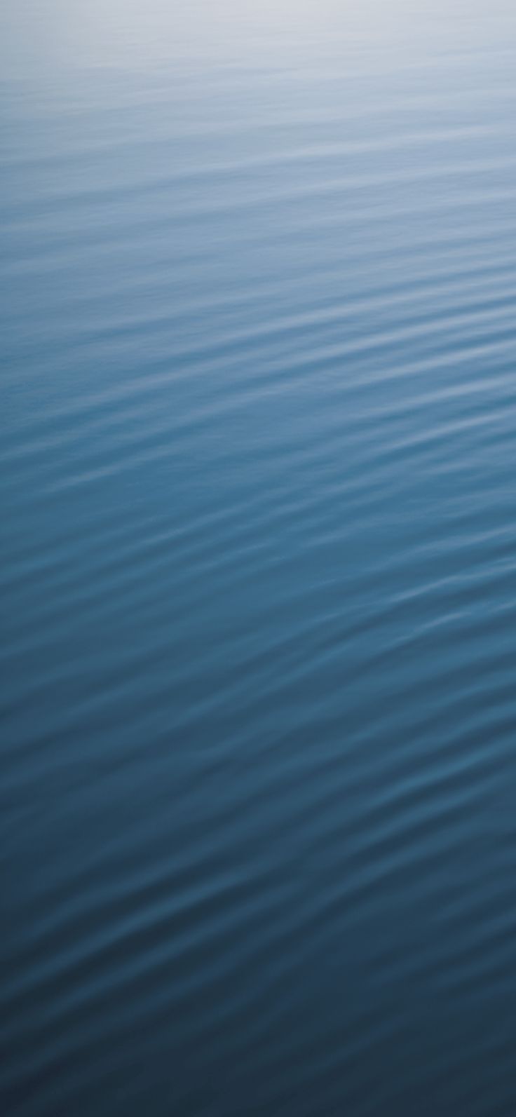 the water is very calm and blue with ripples on it's surface, as seen from above