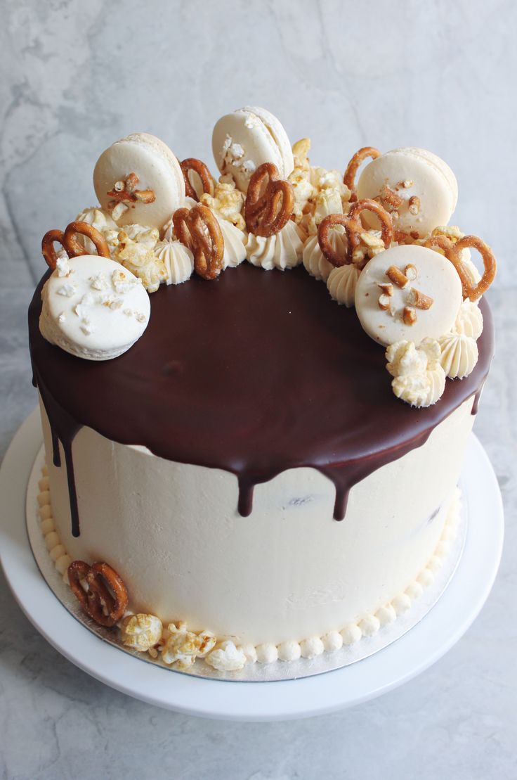 a chocolate cake with white frosting and pretzels on top, sitting on a plate