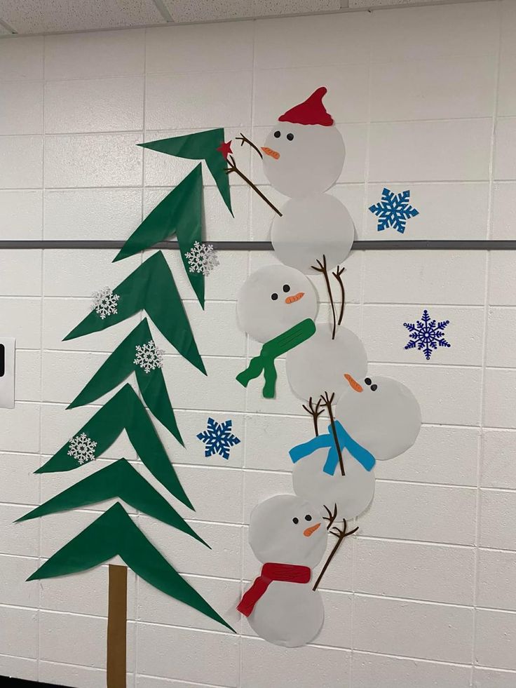 snowmen and trees made out of paper on a bulletin board in a classroom setting