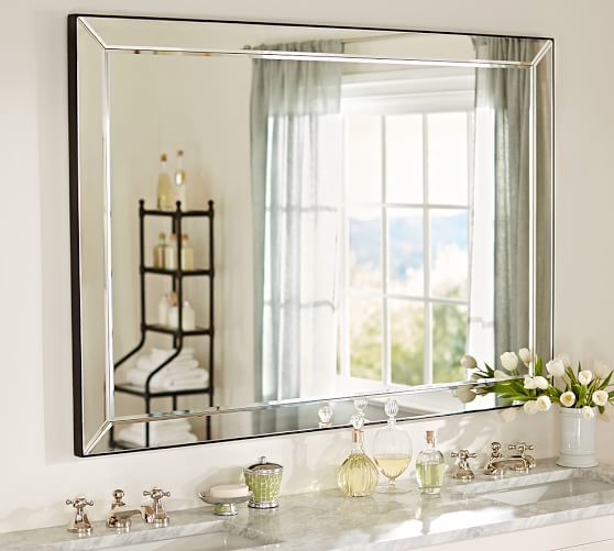 a bathroom sink sitting under a large mirror next to a white counter with flowers on it