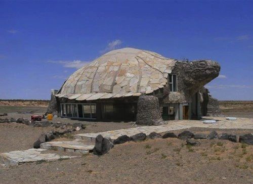 an unusual house in the desert with a tortoise shell on it's roof