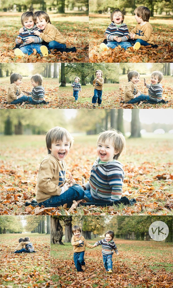 two young boys playing in the leaves with each other and smiling at the camera,