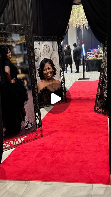 a red carpeted area with black curtains and pictures on the wall, in front of people