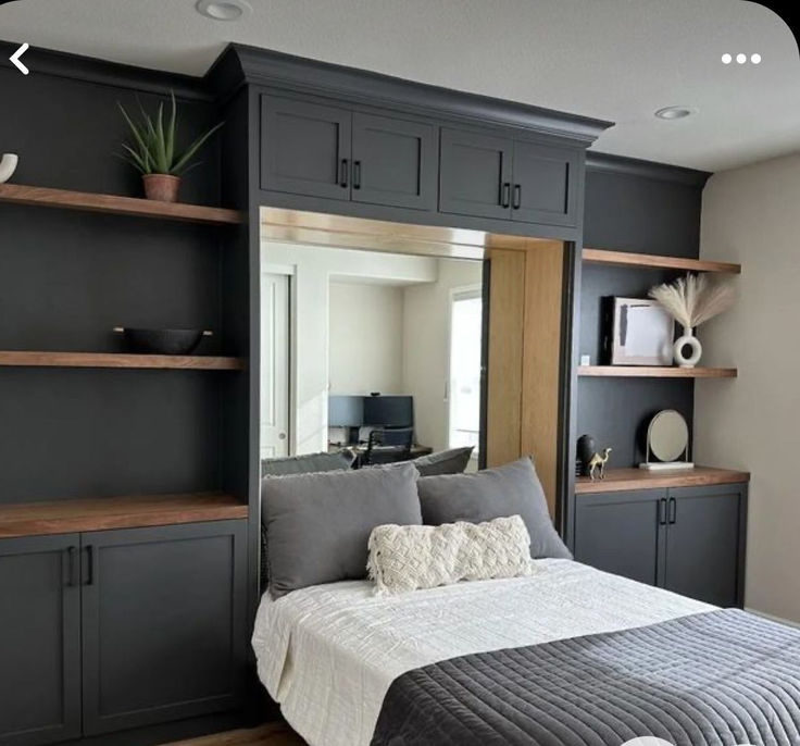 a bed sitting in a bedroom next to a wall mounted bookcase and shelves filled with books