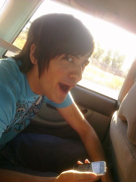 a woman sitting in the back seat of a car holding a cell phone and making a funny face