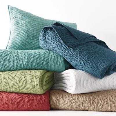 folded towels and blankets stacked on top of each other in various colors, sizes and shapes