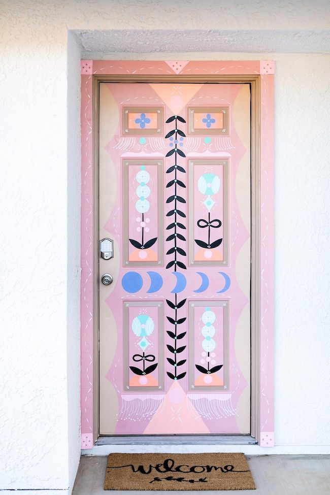 a pink door with an arrow painted on it and the words welcome written in front