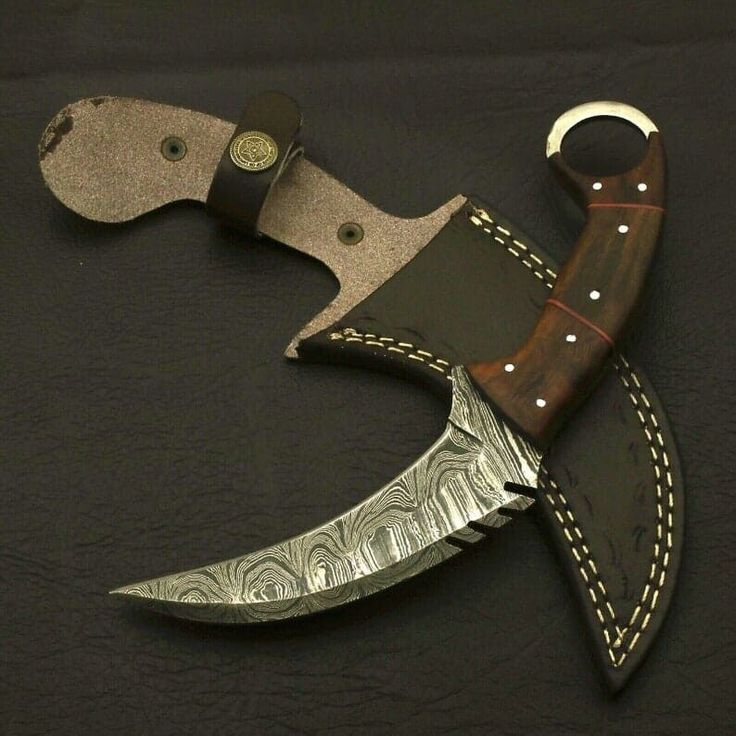 a knife that is sitting on top of a black surface with a brown leather handle