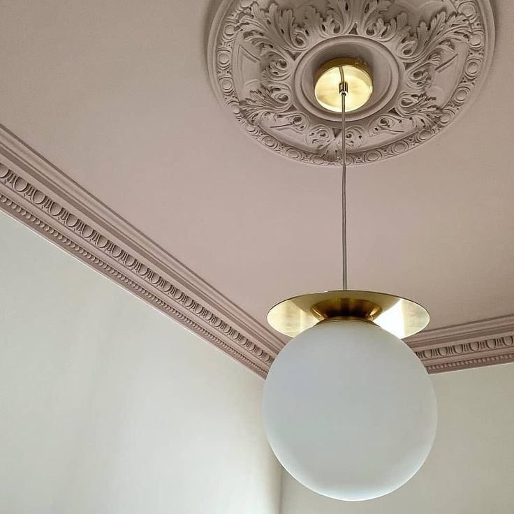 a light fixture hanging from the ceiling in a room with white walls and trimmings