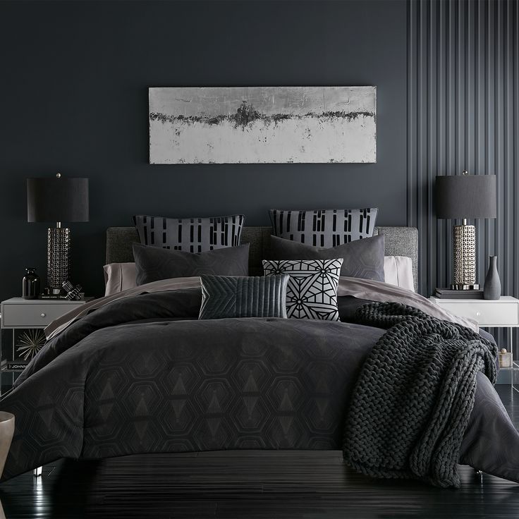 a bedroom with black walls and grey bedding