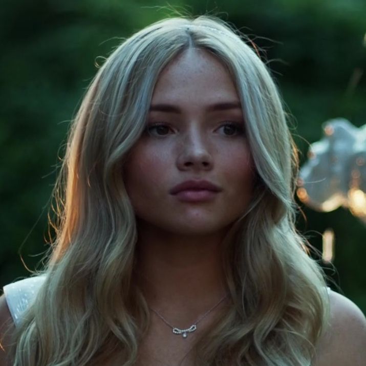 a woman with long blonde hair is looking at the camera