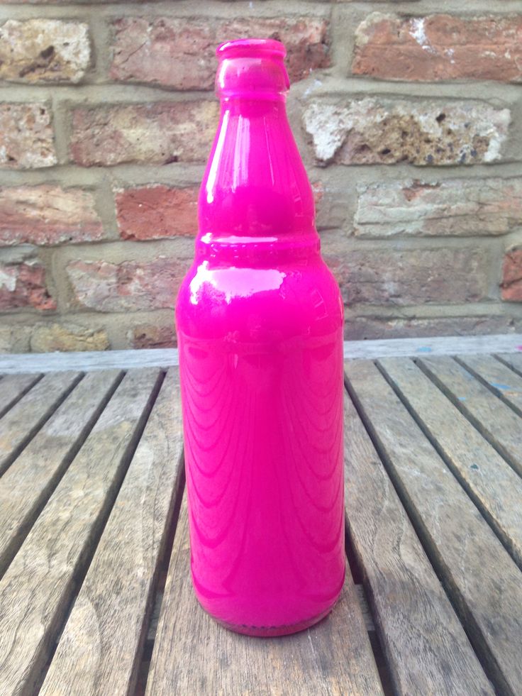 a bright pink plastic bottle sitting on top of a wooden table next to a brick wall