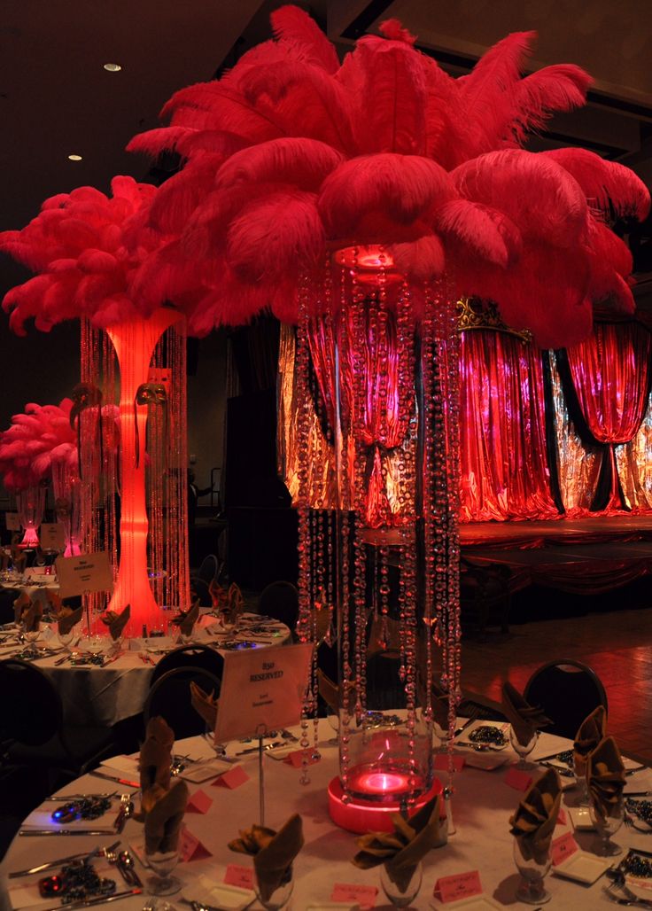 the tables are decorated with red feathers and place settings