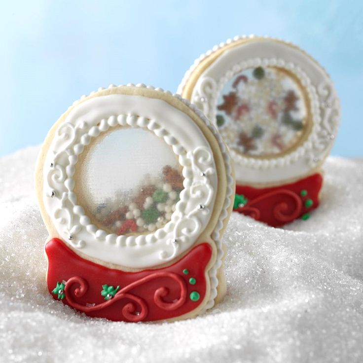 two decorated cookies sitting on top of snow covered ground