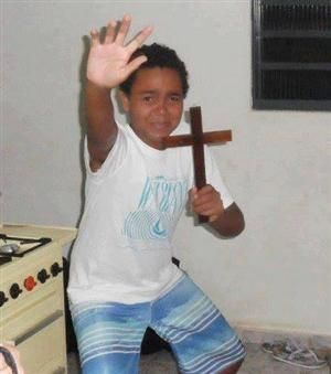 a young boy holding a cross in his hand and pointing it at the camera with both hands