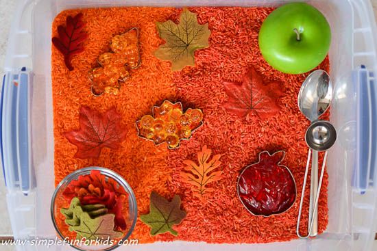 a plastic container filled with food on top of a wooden table next to an apple