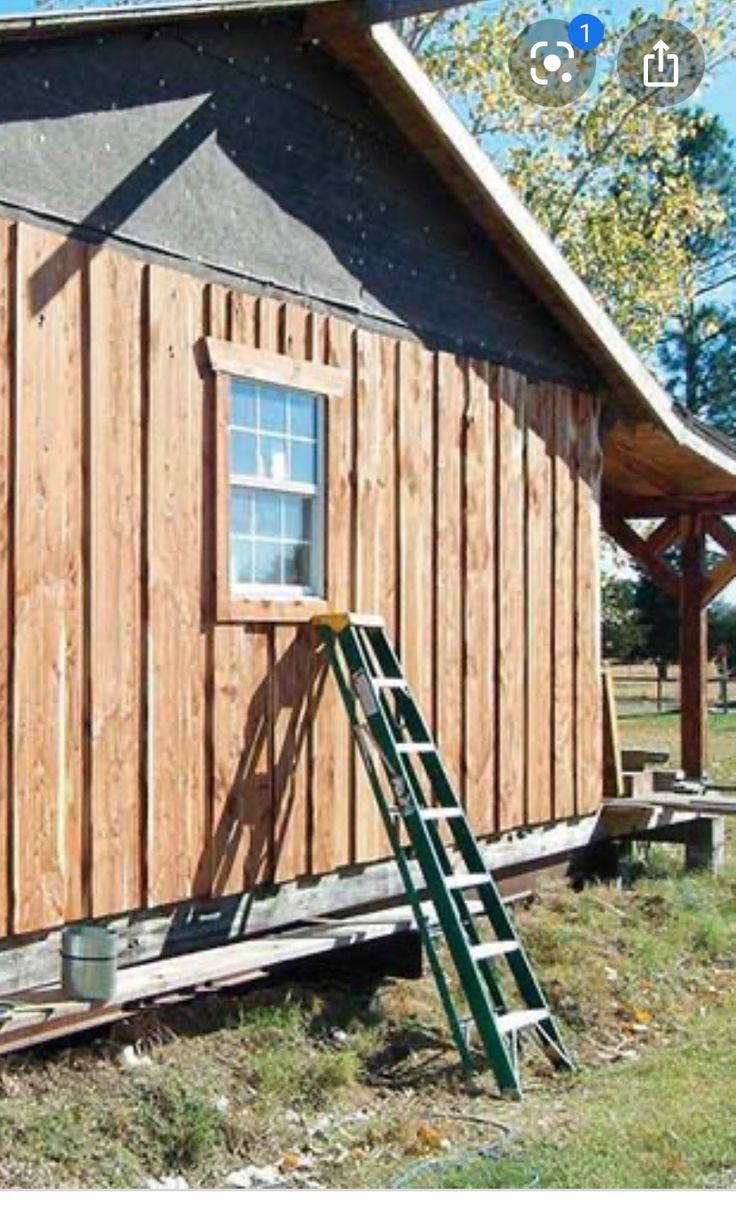 a small wooden cabin with a ladder to the side and a window on the outside