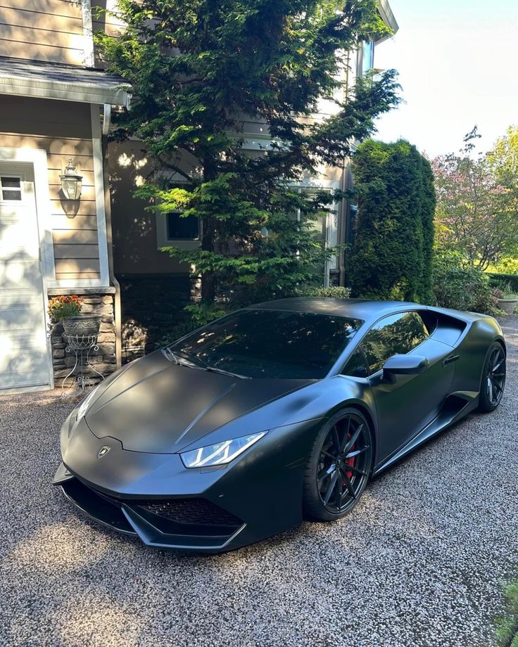 a black sports car parked in front of a house