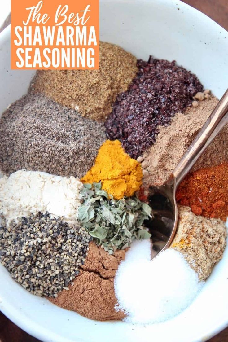 a white bowl filled with different types of seasoning and spices on top of a wooden table