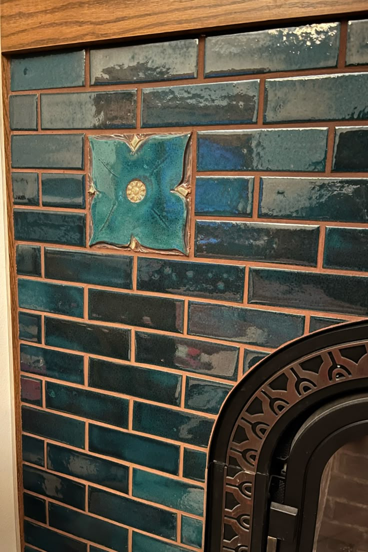 a blue and green tiled wall next to a fire place