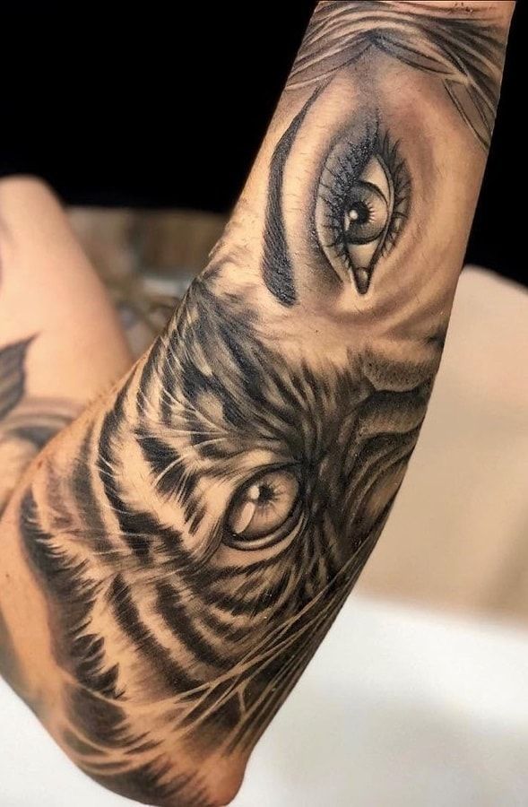 a close up of a person's arm with a tiger tattoo on it and an eye