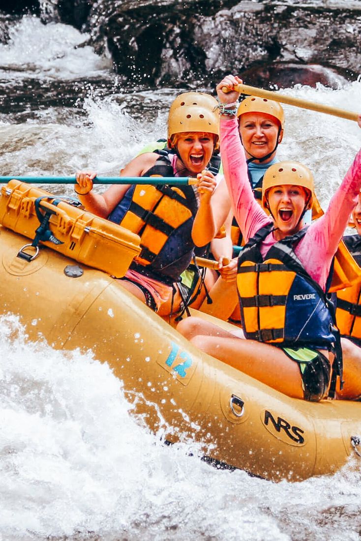 three people are rafting down a river in the middle of white water rapids with their arms up