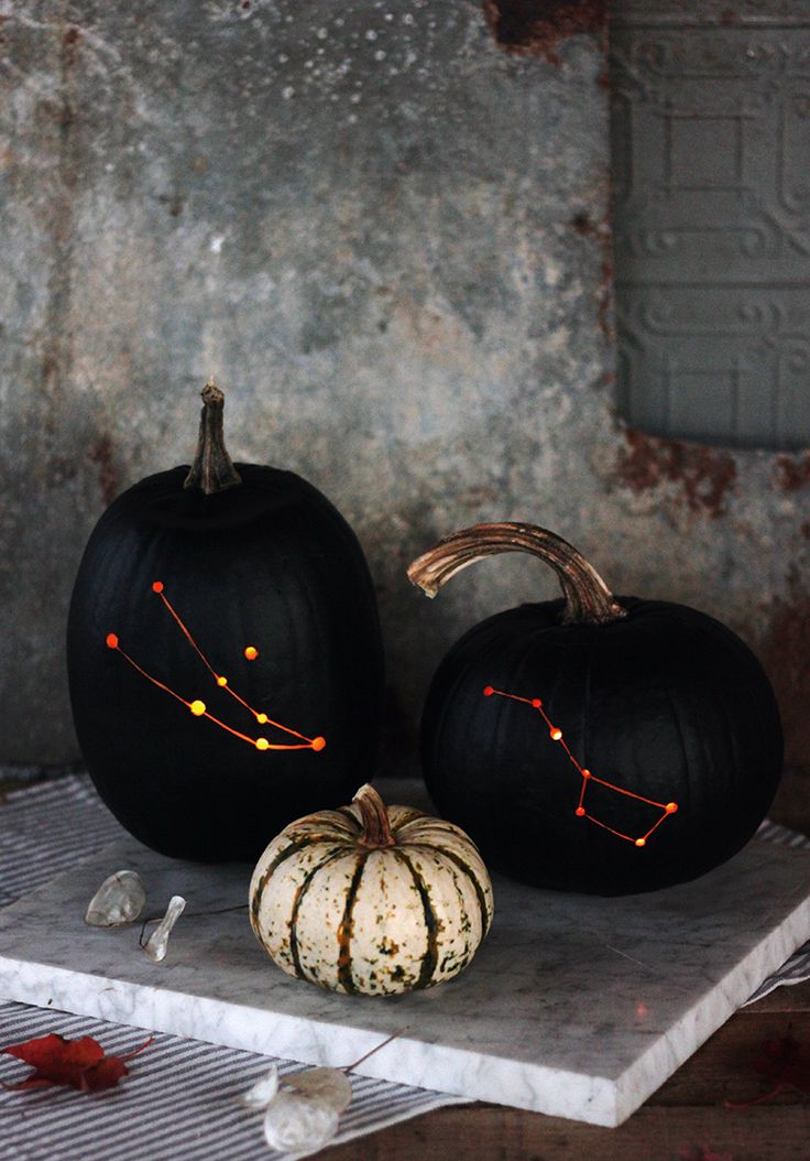 two pumpkins sitting on top of a table with the zodiac sign painted on them