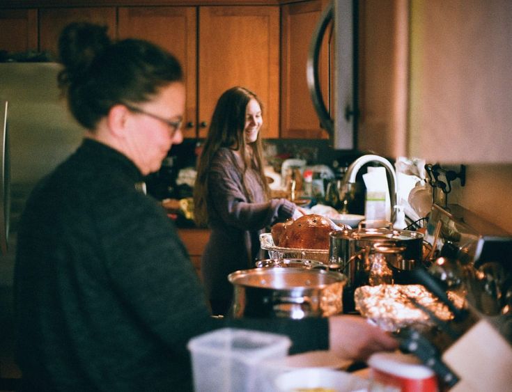 two women standing in a kitchen preparing food