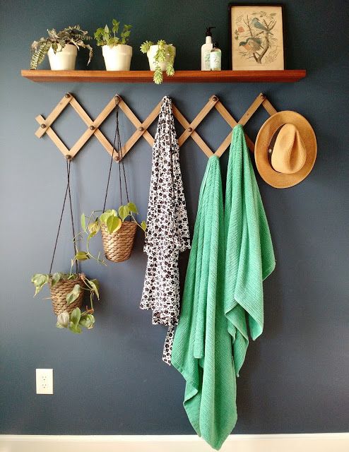 a coat rack with towels, hats and plants hanging from it's hooks on the wall