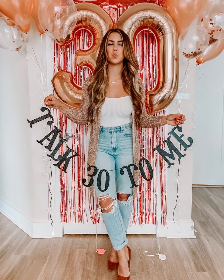 a woman standing in front of balloons with the number twenty on it