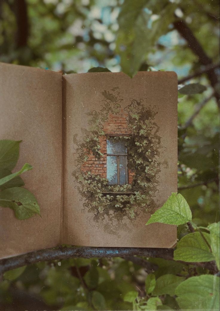 an open book sitting on top of a tree branch with leaves around it and a window in the middle