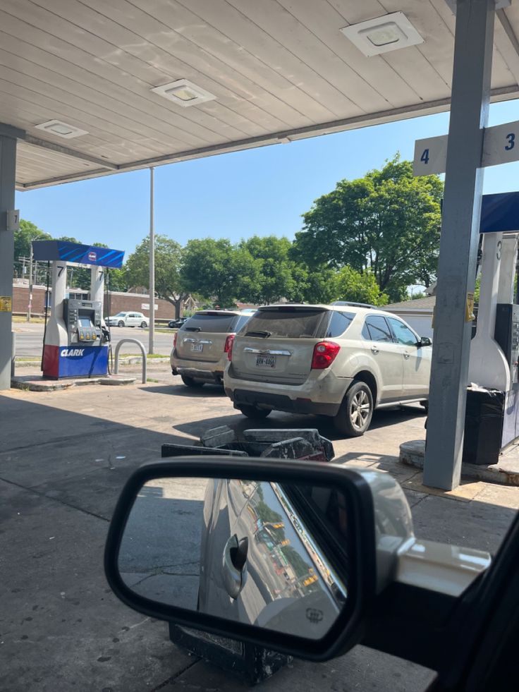 cars are parked at a gas station with no one in the car seat or onlookers