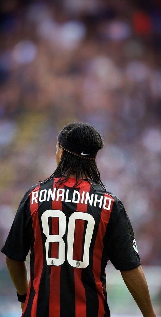 a man with long hair wearing a black and red striped shirt is standing in front of a crowd