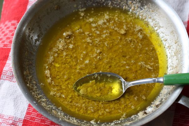 a spoon in a bowl filled with yellow liquid