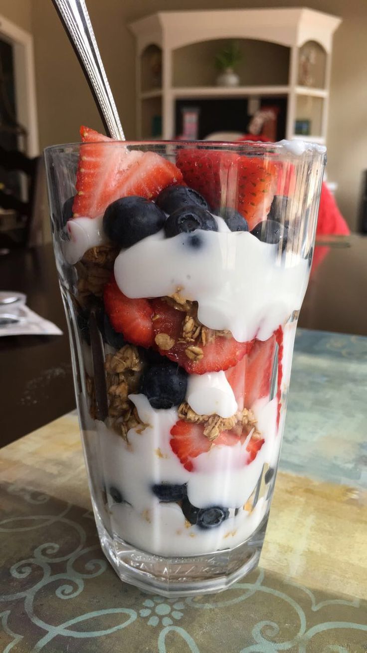 yogurt, strawberries and granola in a glass on a table with a spoon