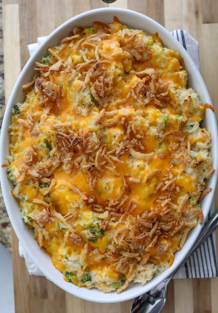 a casserole dish with cheese and broccoli in it on a wooden table