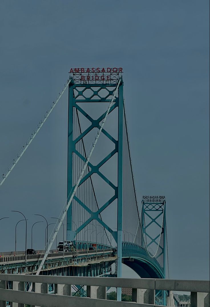 a large bridge that has a sign on the top and some cars driving across it