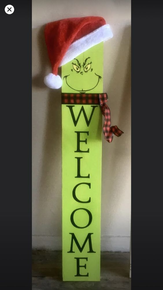 a green welcome sign with a santa hat on it's head and the words welcome