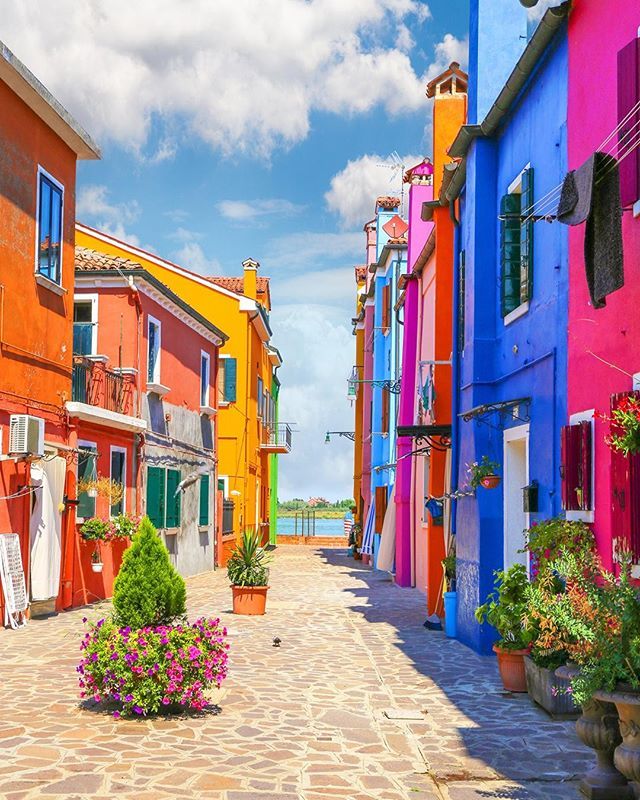 an empty street with colorful buildings and potted plants