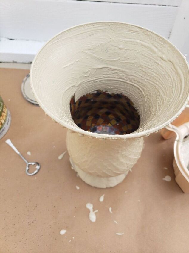 a white vase sitting on top of a table next to other dishes and utensils