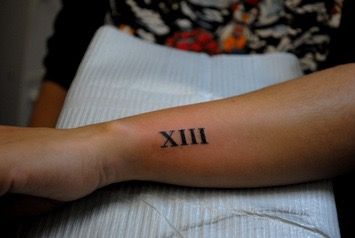 a woman's arm with a roman numeral tattoo on it