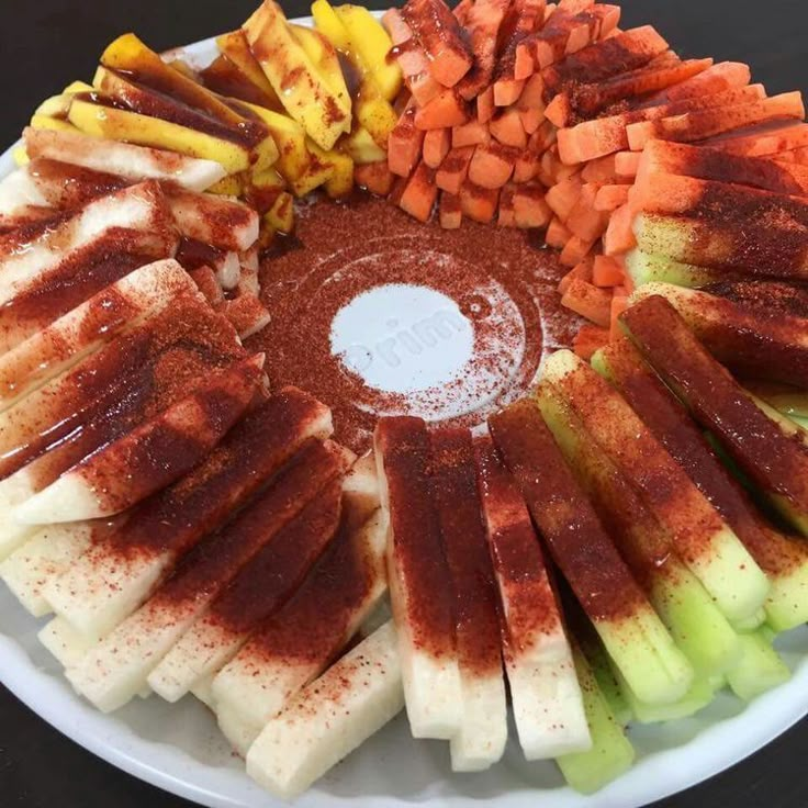 an assortment of cut up vegetables arranged in a circle on a white plate with brown sauce