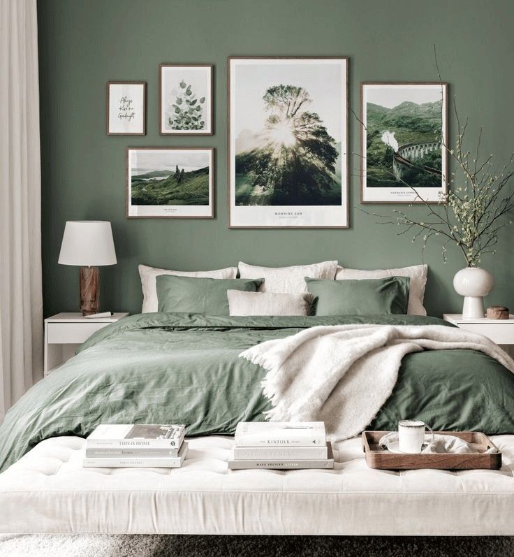 a bedroom with green walls and pictures on the wall above the bed in front of it